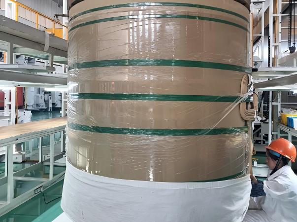 Fotograf&iacute;a del taller que muestra el sistema de protecci&oacute;n integrado de Juhong Packing para rollos de papel industriales gigantes. El proceso combina una pel&iacute;cula estirable LLDPE de alto rendimiento para un sello resistente a la humedad y a las manchas con certificaci&oacute;n AAR (ID: 124) PET Fleje para una integridad estructural de alta resistencia. Como redactor de normas nacionales para sellos Fleje (GB/T 39040—2020), Juhong garantiza una log&iacute;stica sin p&eacute;rdidas para las f&aacute;bricas de papel m&aacute;s grandes del mundo durante el tr&aacute;nsito mar&iacute;timo y ferroviario.